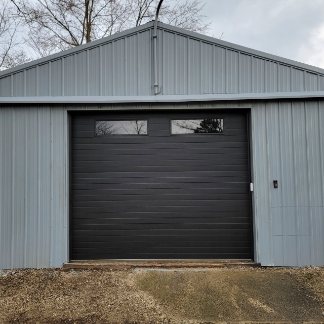 Black garage door on gray metal building